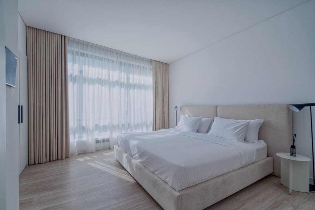 Minimal bedroom with crisp white linen and floor-to-ceiling curtains