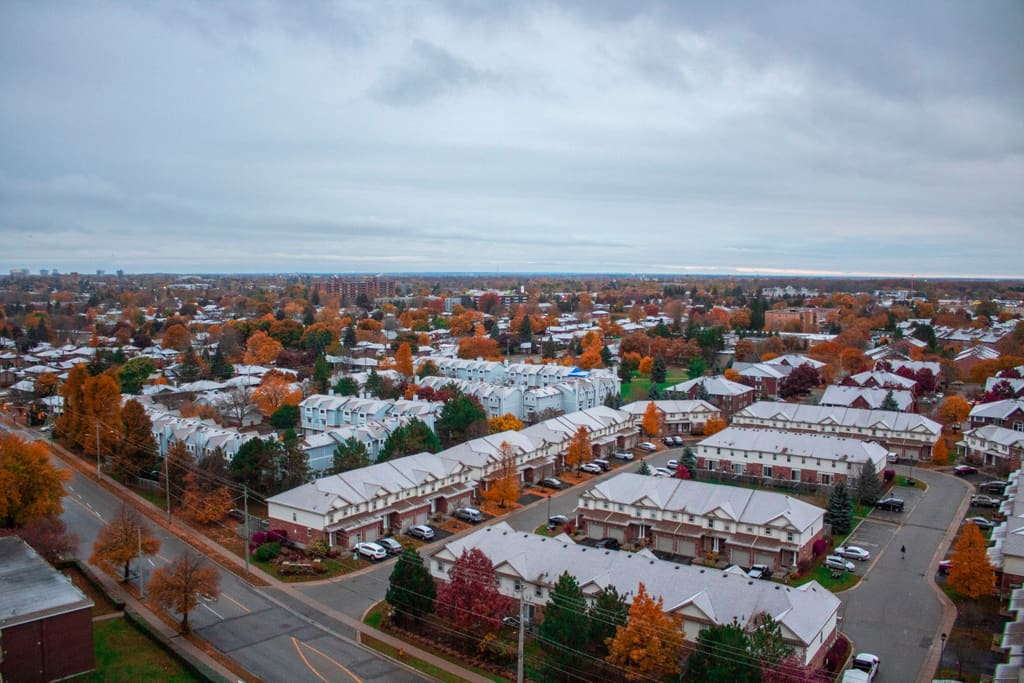 Aerial view over Kitchener townhouse streets in autumn, rooftops dusted with the first snow
