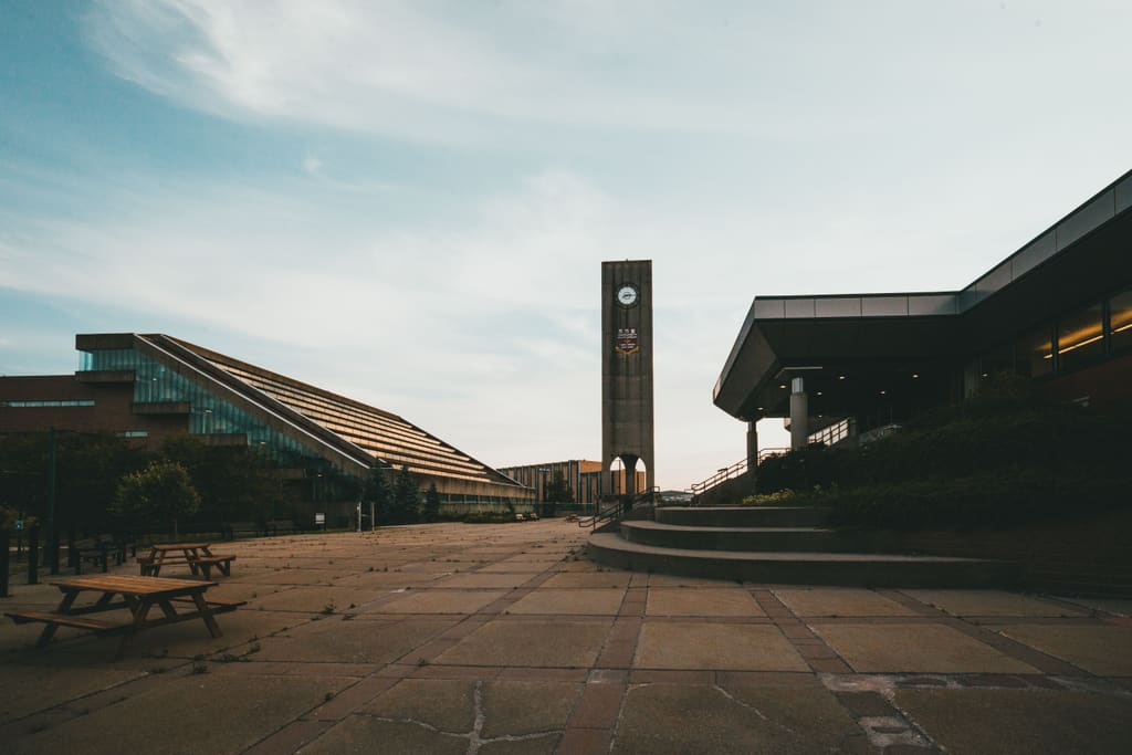 University campus plaza with a concrete clock tower at dusk