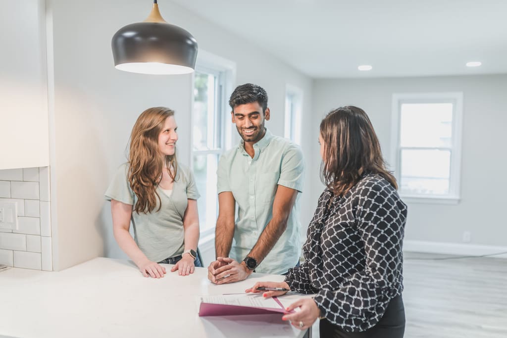 Three people reviewing documents together at a kitchen island