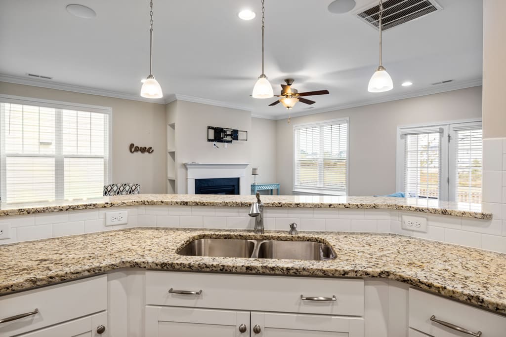 Listing photograph of a bright kitchen with granite counters and pendant lighting