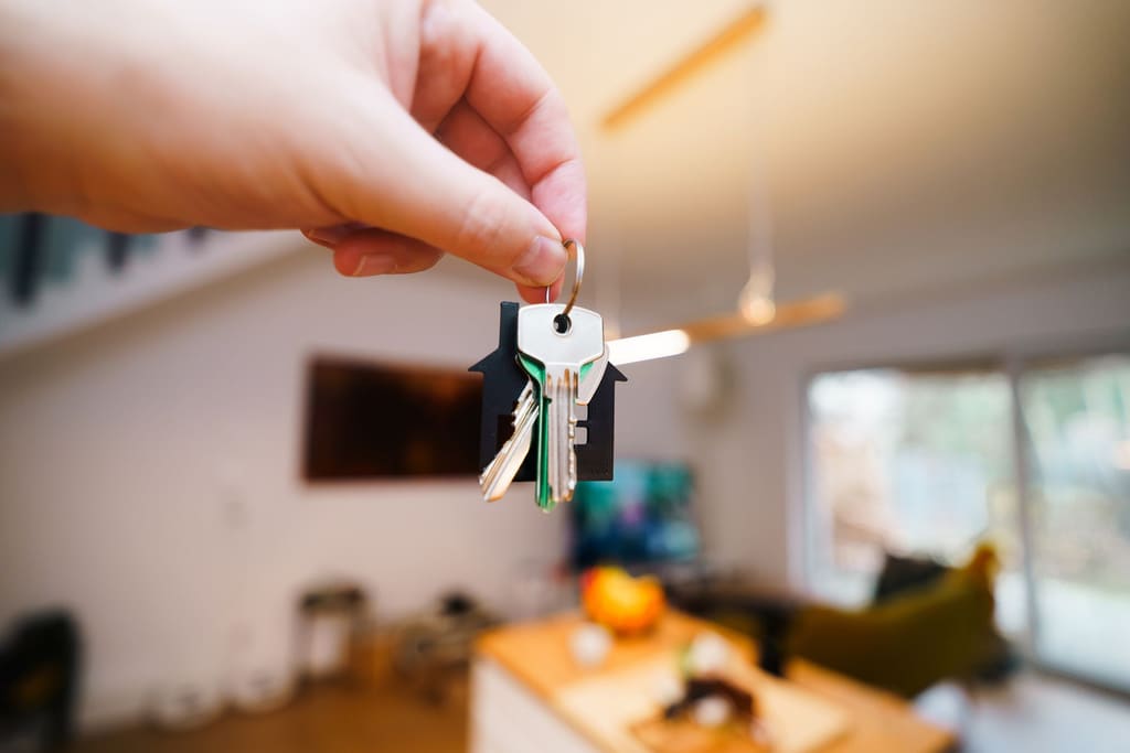 Hand holding house keys inside a bright, modern rental