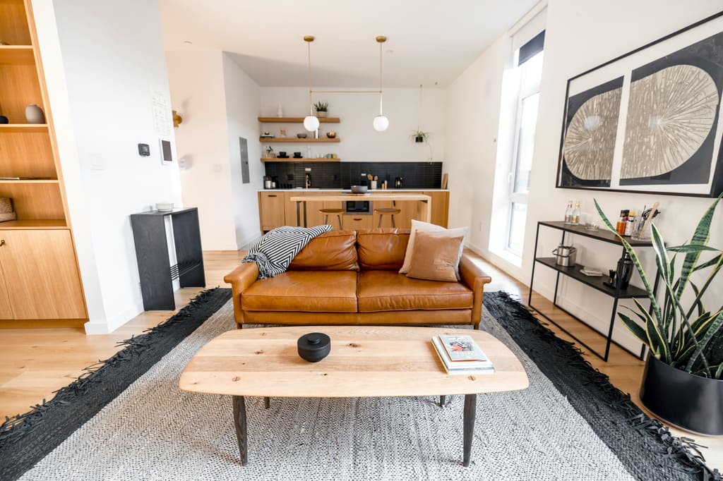 Bright open-plan living room with a leather sofa and a kitchen behind it