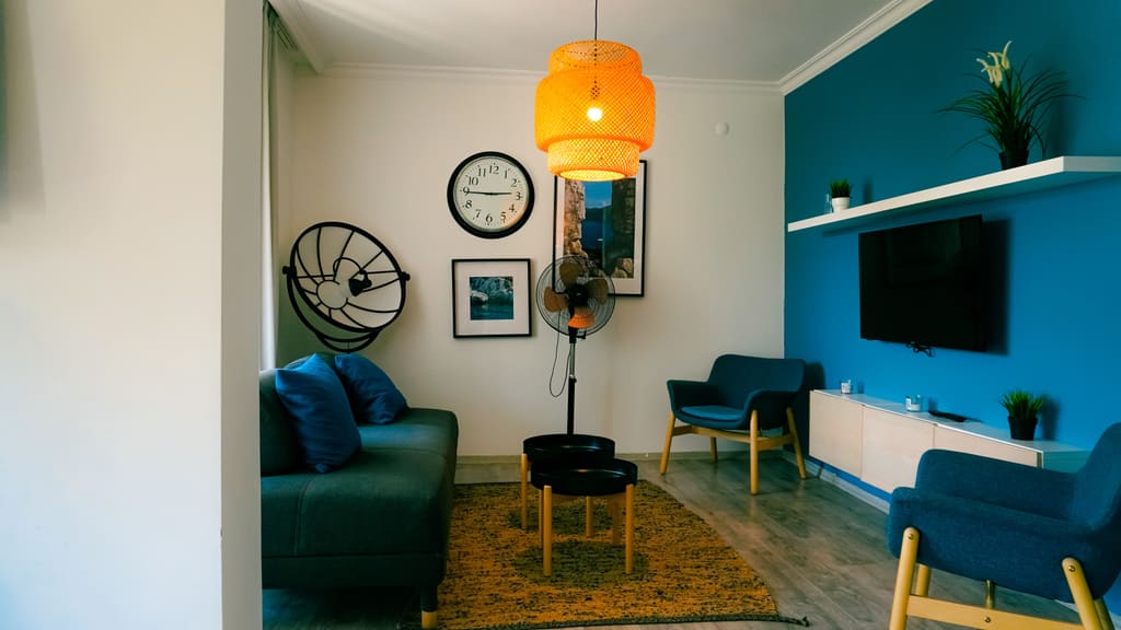 Furnished living room with a teal feature wall, hanging lamp and wall-mounted television