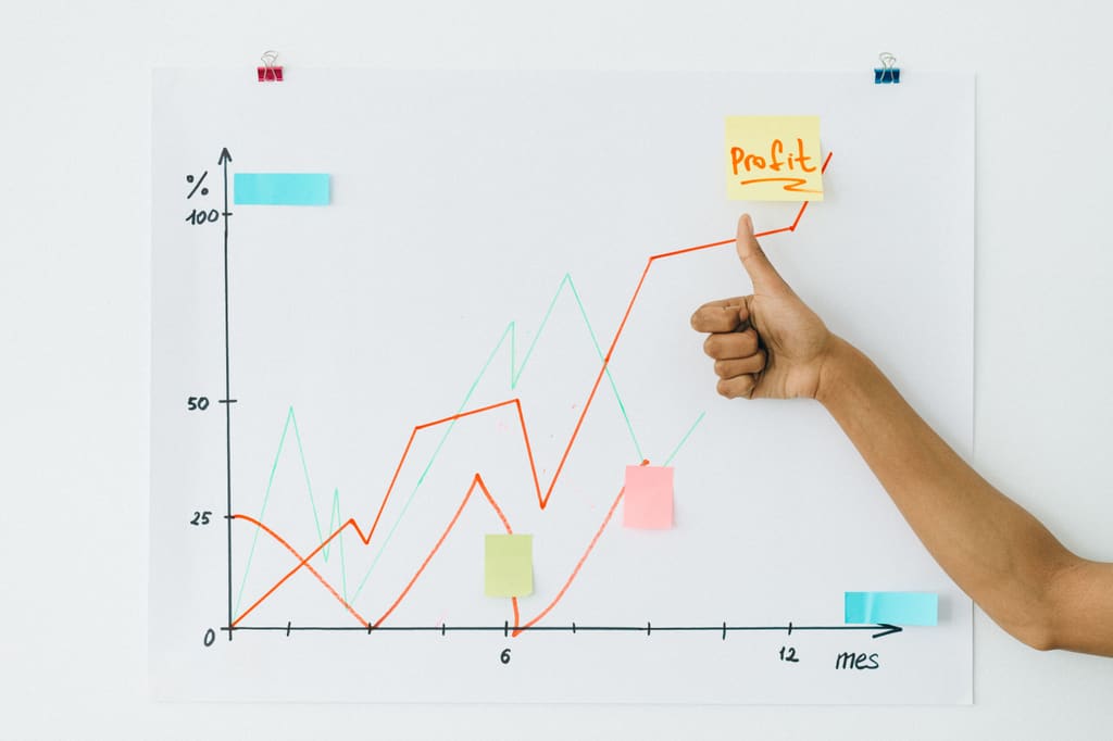 Hand pointing at a rising revenue line drawn on a whiteboard